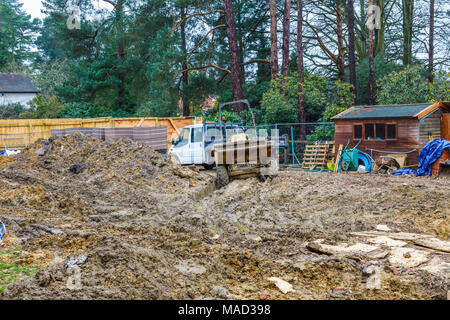 Dumper und weißen Van auf einem Schlammigen aufgewühlten bis Wohnungsbau Website in Surrey im Südosten Englands in feuchten, schlechtes Wetter Stockfoto