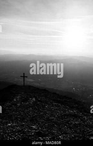 Kreuz auf dem Gipfel des Mt. Serrasanta (Umbrien, Italien), mit Sun niedrig am Horizont Stockfoto