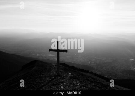 Kreuz auf dem Gipfel des Mt. Serrasanta (Umbrien, Italien), mit Sun niedrig am Horizont Stockfoto