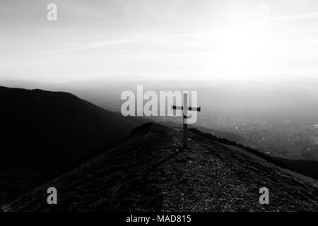 Kreuz auf dem Gipfel des Mt. Serrasanta (Umbrien, Italien), mit Sun niedrig am Horizont Stockfoto