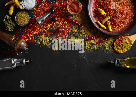 Kochen mit frischen Gewürze mit großen und kleinen Schalen von Spice auf einem Schwarzen Tisch mit Pulver verschütten auf seiner Oberfläche, Ansicht von oben mit Copyspace Stockfoto