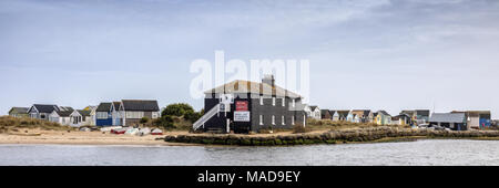 Ein Blick auf das Schwarze Haus und Strandhütten auf Mudeford Spit aus Mudeford Quay, Dorset, England, UK. Strand Hütten hier sind die teuersten in Großbritannien. Stockfoto