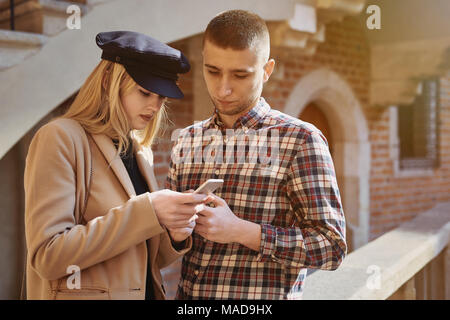 Junge und Mädchen schauen Sie sich das Telefon und sprechen miteinander Stockfoto