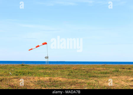 Windstärke (Windsack) gegen das dunkle Meer und blauer Himmel Stockfoto
