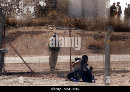 Bilin, Palästina, 3. Dezember 2010: Wheelchaired Demonstrant und riffle IDF-Soldaten durch ein Sicherheitszaun während der wöchentlichen Demonstrationen gegen Pal hingewiesen Stockfoto