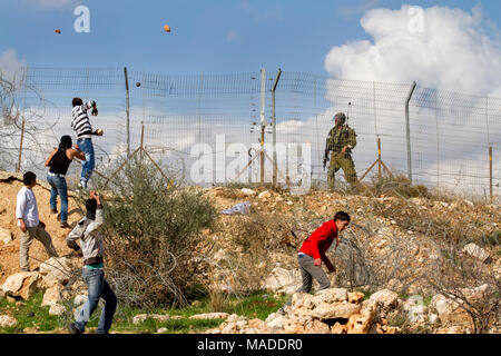 Bilin, Palästina, 1. Januar 2011: Palästinensische Jugend wirft Steine auf israelische Soldaten in Bilin während der Demonstration gegen die israelische Präsenz in West B Stockfoto