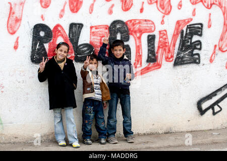 Bilin, Palästina, 31. Dezember 2010: Palästinensische Kinder stehen auf der Straße von bilin vor 'blutigen' Palästina Graffiti. Stockfoto