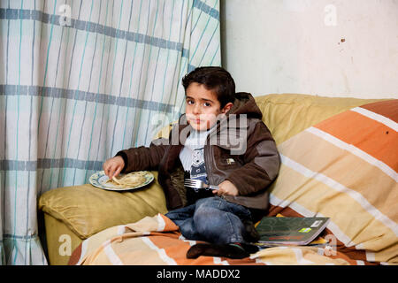 Bilin, Palästina, 7. Januar 2011: palästinensischer Junge ist ein Mittagessen in seinem Haus. Stockfoto