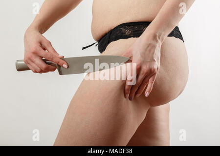 Schneiden mit dem Messer überdimensionale weibliche Gesäß mit Cellulite auf weißem Hintergrund Stockfoto