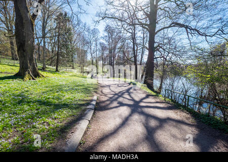 Nicht erkennbare Personen genießen Sie Frühling Atmosphäre im City Park entlang der Fluss Motala in Norrköping, Schweden. Stockfoto