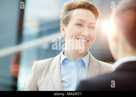 Lächelnd Geschäftsfrau Hören zu einem anderen Mitarbeiter während der Diskussion der Arbeit Momente oder Ideen bei der Sitzung Stockfoto