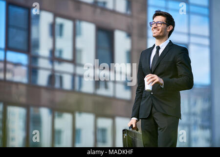 Fröhliche Banker in formale Kaffee auf seinem Weg in den Morgen zu arbeiten Stockfoto