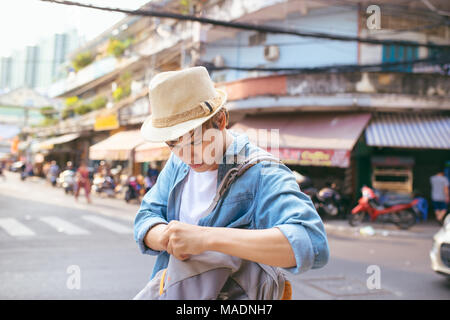 Asiatische männlichen Reisenden umgekippt. Verloren einige wichtige Sache Konzept in der Straße. Stockfoto