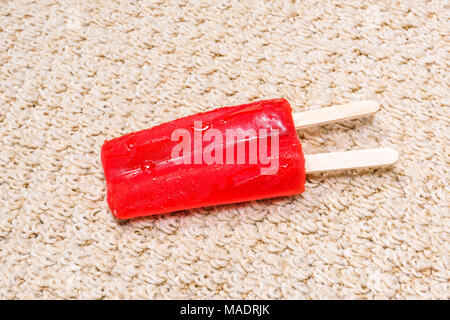 Einem Time Lapse-Videorecorder eines schmelzenden Popsicle auf weißen Teppich zeigt die eisigen behandeln in einem klebrigen Saft schmelzen und rechts in den Teppich zu absorbieren. Stockfoto