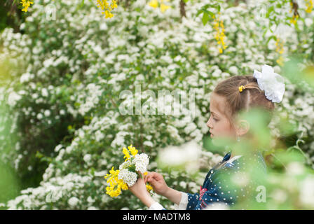 Schöne Mädchen sammelt Blumenstrauß unter blühenden Vegetation im Frühjahr Stockfoto