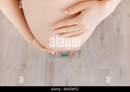 Closeup schwangere Frau auf Skalen, die Ansicht von oben. Schwangerschaft, Gesundheitswesen, der gewichtszunahme Konzept Stockfoto