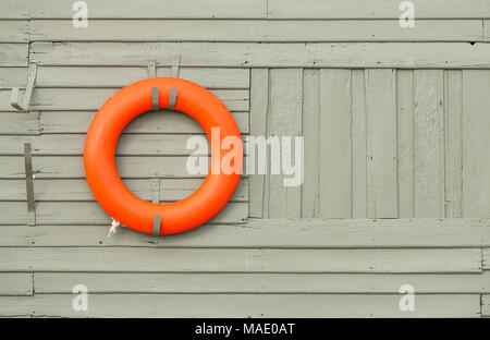 Orange Rettungsring hängen graue Holzwand Hintergrund Stockfoto