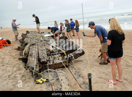 März 30, 2018-Ponte Vedra Beach, Florida, United States - Schaulustige beobachten, wie sich die Forscher ein Schiffswrack, das am 28. März 2018 nach dem Landgang aus Ponte Vedra Beach in Florida gewaschen entdeckt wurde. Ein Team aus der St. Augustine Leuchtturm archäologische Maritime Programm ist der Prüfung und Messung der 48-Fuß-langen hölzernen Überreste, die geglaubt werden, von einem Handelsschiff, dass Ladung entlang der Atlantikküste der USA während Anfang bis Mitte der 1800er transportiert zu haben. (Paul Hennessy/Alamy) Stockfoto