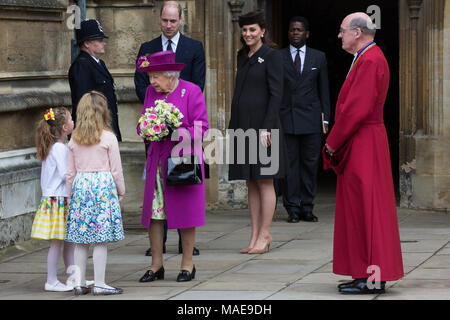 Windsor, Großbritannien. Der 1. April 2018. Madeleine Carleston und Amelia Vivian, beide im Alter von 6, geben die traditionellen posies von Blumen an die Königin, als sie den Ostersonntag Service in der St. George's Chapel in Windsor Castle verlässt. Credit: Mark Kerrison/Alamy leben Nachrichten Stockfoto