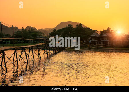 Nam Song Fluss mit Holzbrücke bei Sonnenuntergang in Vang Vieng, Laos. Vang Vieng ist ein beliebtes Reiseziel für Abenteuer Tourismus in einem Kalkstein Karst Landsc Stockfoto