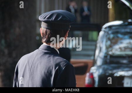 Japanische Tokio Taxifahrer zu seinem schwarzen Taxi links Stockfoto