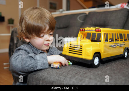 Montreal, Kanada, 31, März, 2018. Junge 3-jährigen Jungen drinnen spielen mit einem Spielzeug Schule Bus. Credit: Mario Beauregard/Alamy leben Nachrichten Stockfoto