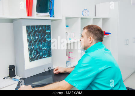 Männlicher Arzt auf Röntgenbild der Halswirbelsäule in seinem Büro. Osteopathie, Chiropraktik, Physiotherapie. Healthcare, Röntgen, Menschen und Medizin Stockfoto