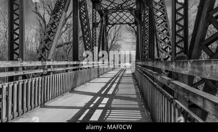 Blick auf eine alte Eisenbahnbrücke umgewandelt in einen Park Trail; Missouri, Mittelwesten; Schwarz und Weiß; lange Schatten Stockfoto