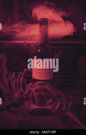 Die Hände eines menschlichen Skeletts mit einem Glas Wein und einer Schreibmaschine. Stillleben Foto. Getönt Stockfoto