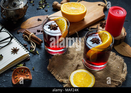 Das Konzept der hausgemachten Glühwein. Glühwein in einem Glas auf einem dunklen Stein Hintergrund. Stockfoto