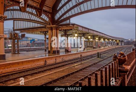 Eine reich verzierte 19 Plattform und Vordach an der Bahnhof York in der Morgendämmerung. Pfützen sind auf der Plattform und eine Kugel ist im Vordergrund. Stockfoto