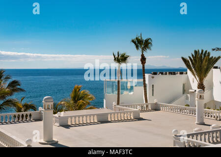 Blick über die Dächer der Häuser mit Palmen in Puerto del Carmen auf Lanzarote, Spanien zum Meer. Stockfoto