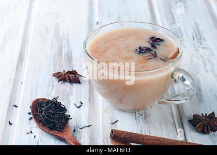 Heiße Tasse schwarzen Tee mit Milch und Zimt auf einen alten Holztisch, selektiver Fokus Stockfoto