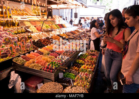 Besucher bewundern die große Auswahl an getrockneten Früchten, Nüssen und Schokolade zum Verkauf in La Boqueria Markt in der Nähe von La Rambla, Barcelona, Spanien Stockfoto