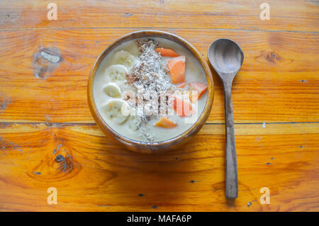 Smoothie Schale in Scheiben geschnittene Bananen, Papaya, Rosinen, Orangen und Hafer für eine gesunde vegane Frühstück für das Sommer Körpers Ziele Stockfoto