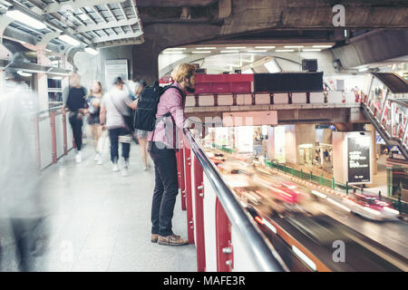 Hipster bärtigen Mann in den Bahnhof mit Menschen Bewegung Hintergrund, während in der Nacht unterwegs. Stockfoto