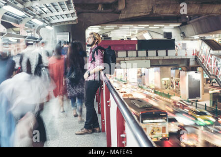 Hipster bärtigen Mann in den Bahnhof mit Menschen Bewegung Hintergrund, während in der Nacht unterwegs. Stockfoto