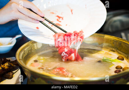 Stäbchen einfügen in Scheiben geschnittene Lamm in kochendes Hotpot Stockfoto