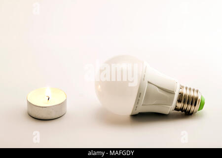 Fortschritte bei der Beleuchtung mit Kerze angezeigt und LED-Lampe. Entwicklung der Beleuchtung, der Konfrontation verschiedener Generationen von Lichtquellen. Moderner Techno Stockfoto