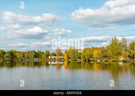 Schönen See mit Spiegel Reflexionen im klaren Wasser an einem sonnigen Tag. Ruhige Landschaft mit See, bewölkter Himmel, und Bäume symmetrisch spiegelt sich in der Stockfoto