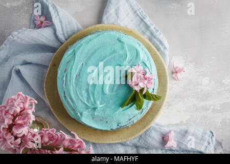 Blau stilvolle Kuchen mit Blumen und Minze. Platz kopieren, Ansicht von oben. Stockfoto