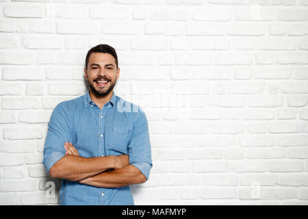 Portrait von glücklichen italienischen Mann lächelnd gegen weiße Wand als Hintergrund und Kamera. Stockfoto