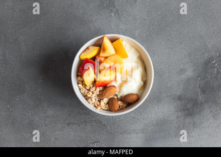 Hausgemachte Haferflocken Müsli mit Joghurt und Pfirsiche in Schüssel für gesundes Frühstück. Müsli Müsli und Obst frühstück Schüssel mit Joghurt. Stockfoto