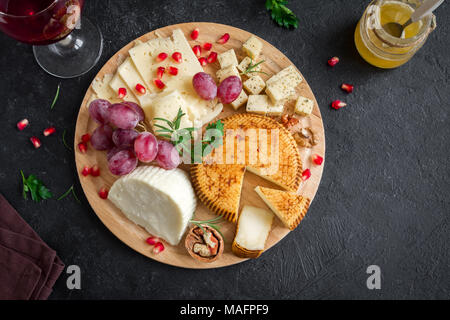 Käseplatte mit verschiedenen Käsesorten, Trauben, Nüsse über schwarzen Hintergrund, kopieren. Italienischen Käse und Obstteller mit Honig und Wein. Stockfoto