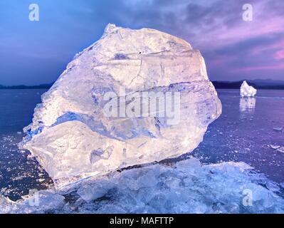 Shining faltige Oberfläche gebrochenem Eis, frische eisige Stücke auf flachen frost Boden. Bunte winter Sonnenuntergang. Stockfoto