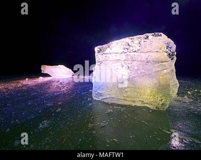 Shining faltige Oberfläche gebrochenem Eis, frische eisige Stücke auf flachen frost Boden. Bunte winter Sonnenuntergang. Stockfoto