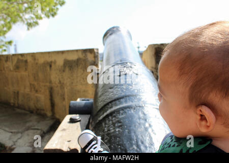 Sechs Monate altes Baby Junge sitzt auf dem Canon Stockfoto