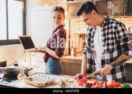 Frau arbeitet zu Hause Remote aus dem Büro, weil Sie ein Freiberufler ist, als ihr Mann zum Abendessen. Innen-, Studio shot Stockfoto