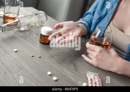 Junge weibliche Droge soziale Probleme am Tisch Entscheidung machen die weißen Pille close-up trinken Whisky sitzen süchtig Stockfoto