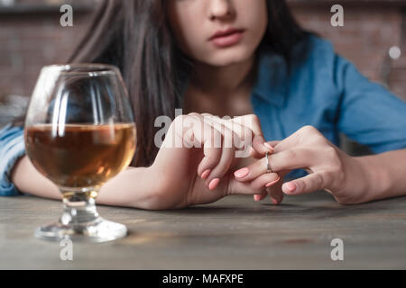 Junge weibliche alkoholische soziale Probleme am Tisch sitzen unter den Ring Familie Probleme Scheidung close-up Stockfoto